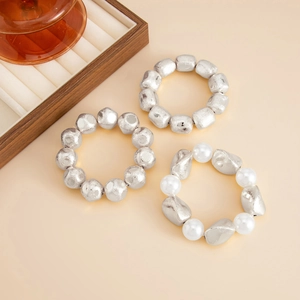 Close-up of beaded resin stretch bracelets with textured silver beads and white pearls