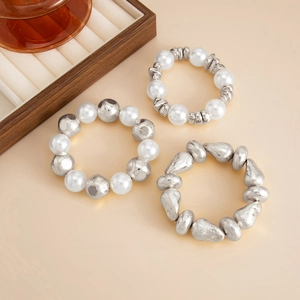 Detailed macro of a three-piece elastic beaded bracelet set with pearls and silver metal