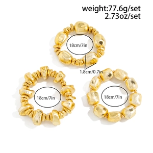 Detailed view of three chunky irregular gold resin beads on elastic bracelets on white