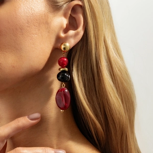 Detail van lange boho-hangers met rood gemarmerde kralen en goudkleurige metalen knopjes