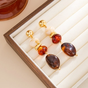 Detail van vintage amberkleurige harskralen en gouden knopjes op een wit sieradendoosje