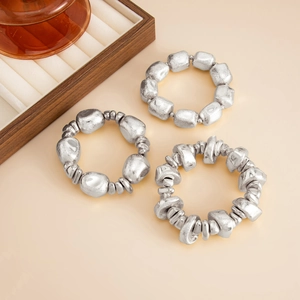 Detail view of three irregular beaded bracelets with matte silver textured finish