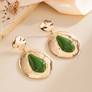 Detail van grote gouden onregelmatige oorbellen met groene hars druppel en vintage look