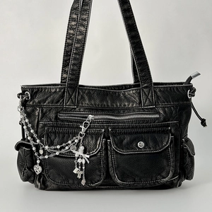 Black faux leather tote bag with silver heart chain and pearl charms in a flat lay view