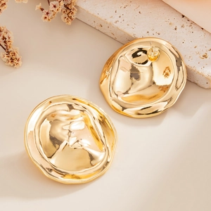 Macro-opname van gouden rimpel metalen ronde oorknopjes op beige getextureerde steen