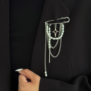 Detail of silver safety pin brooch with tassel chains and pearls on a black suit jacket
