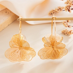 Detail van gouden ginkgo-blad oorbellen met filigraan textuur op een luxe displaystandaard
