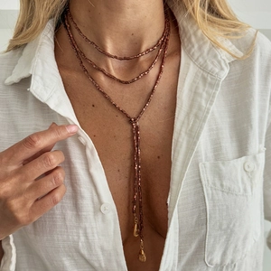 Y-vormige gelaagde ketting met metalen kralen en gouden druppel hanger op een model