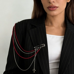 Detail of a punk style fringe brooch with red beads and silver chains on a black suit