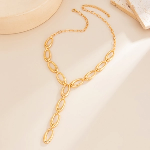 Macro view of gold-tone Y-shaped necklace with oval links on a textured stone surface