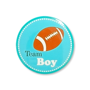 Gros plan du badge Team Boy pour baby shower avec fond bleu et motif de rugby