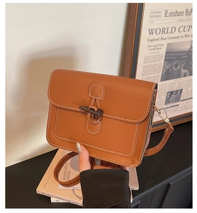Detail of vintage brown tote bag with contrast stitching and unique horn buckle closure