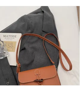 Detailed view of a brown messenger bag with white stitching and a toggle horn button closure