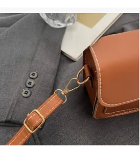 Detail of premium brown leather bag showing white contrast stitching and gold metal hardware