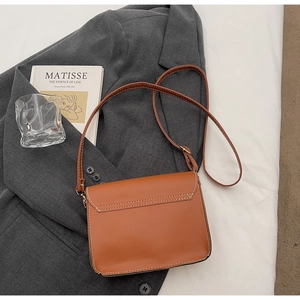 Detailed view of a brown leather crossbody bag with white contrast stitching on fabric
