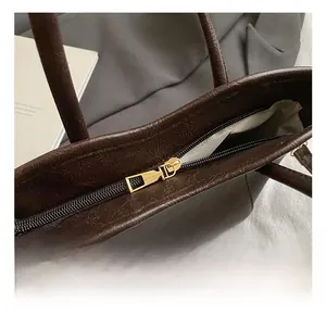 Dettaglio della cerniera superiore e dell'hardware dorato della borsa marrone scuro