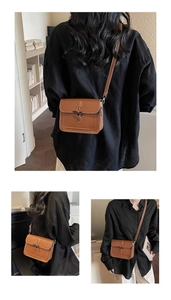 Detailed close-up of brown leather bag featuring contrast stitching and horn buckle