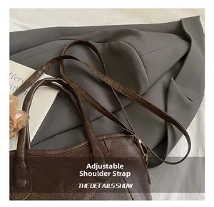 Dettaglio ravvicinato della borsa a secchiello in pelle marrone scuro con tracolla regolabile