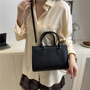 Minimalist black vertical embossed cylinder handbag with silver hardware and shoulder strap