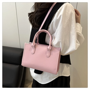 Close-up of pink pleated handbag with tubular handles and shoulder strap on model