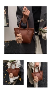 Dettaglio borsa a secchiello in pelle marrone con un simpatico ciondolo a forma di orsetto
