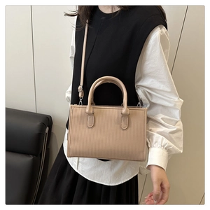 Close-up of minimalist beige tote bag featuring vertical pleated texture and silver hardware