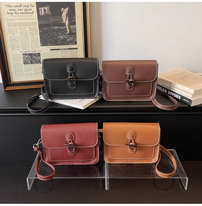 Close-up of four vintage small square bags with horn buckles and white stitching detail