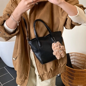 Borsa a secchiello nera minimalista con ciondolo a orso in un elegante selfie allo specchio