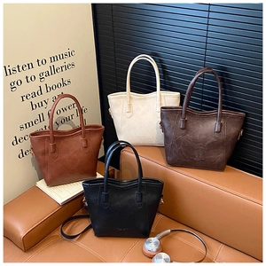 Dettaglio di quattro borse a secchiello minimaliste in pelle nei colori marrone, beige e nero