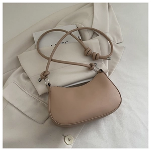 Vista dall'alto della borsa beige a mezzaluna con tracolla a nodo su blazer neutro