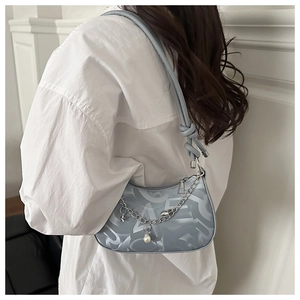 Detail of light blue crescent bag with silver chain, pearl charms, and knotted strap