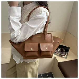 Dettaglio di una borsa tote in pelle marrone con tasche e finiture in metallo oro