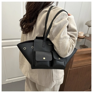 Detail view of black lychee grain tote bag with wing design and golden button flap pockets