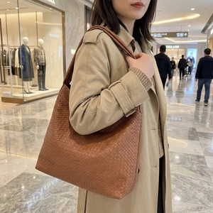 Gros plan d'un sac cabas en cuir tressé marron avec large bandoulière sur un mannequin