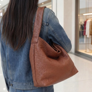Détail d'un sac hobo en cuir tressé marron montrant la texture et le savoir-faire