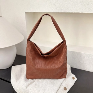 Détail de la texture en cuir tressé Intrecciato marron sur un grand sac hobo