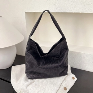 Détail du sac fourre-tout en cuir tressé noir montrant la texture de luxe et le style