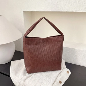 Détail d'un sac à main marron foncé à texture tressée montrant un artisanat de qualité