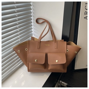 Close-up of brown pebbled leather tote bag with dual front pockets and gold buckle detail