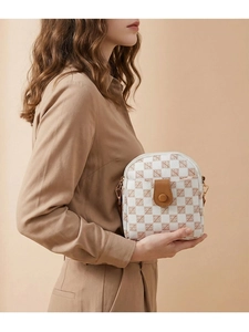Detail of checkered crossbody phone bag featuring brown leather flap and golden metal hooks