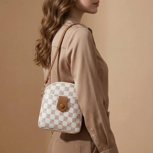 Brown checkerboard crossbody phone bag with leather strap shown on shoulder