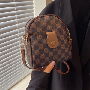 Detail of checkered phone bag featuring gold hardware and flap pocket with brown strap