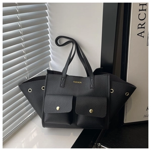 Close-up of black lychee texture tote bag featuring dual front pockets and gold metal studs
