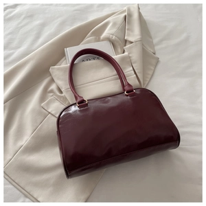Macro shot of high-quality burgundy Boston bag with matte leather texture and gold metal rings