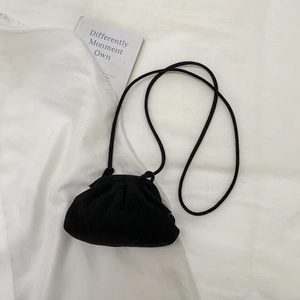 Top-down view of a black pleated cloud-shaped crossbody bag on a white fabric surface