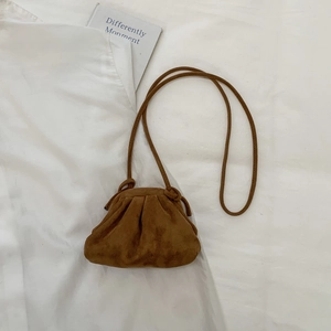 Detailed top view of a brown pleated dumpling bag on a white shirt and book