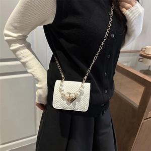 Chic white woven crossbody bag with pearl handle and golden heart clasp on model