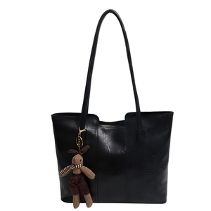 Classic black faux leather tote bag with a brown plush rabbit charm on a white background