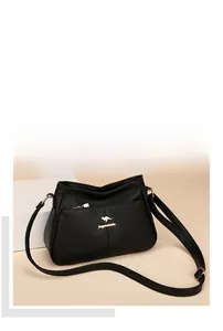 Detailed macro view of soft lychee pattern leather and gold kangaroo logo on black handbag