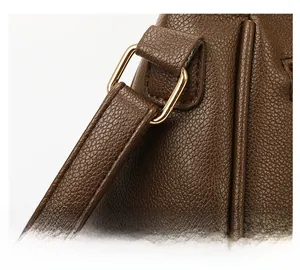 Close-up of golden metal hardware and reinforced stitching on a brown leather bucket bag